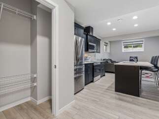 Discover modern living in this stylish basement suite featuring a sleek, dark-cabinet kitchen with stainless steel appliances and a convenient island with seating.