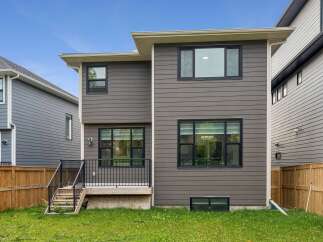 This modern home features a sleek, dark gray horizontal siding exterior, complemented by black-trimmed windows that offer ample natural light.