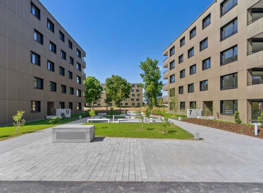 Discover modern living in this contemporary apartment complex featuring sleek, tan-colored facades and abundant natural light.