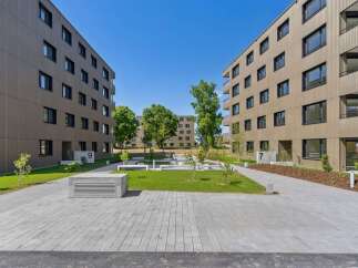 Discover modern living in this contemporary apartment complex featuring sleek, tan-colored facades and abundant natural light.