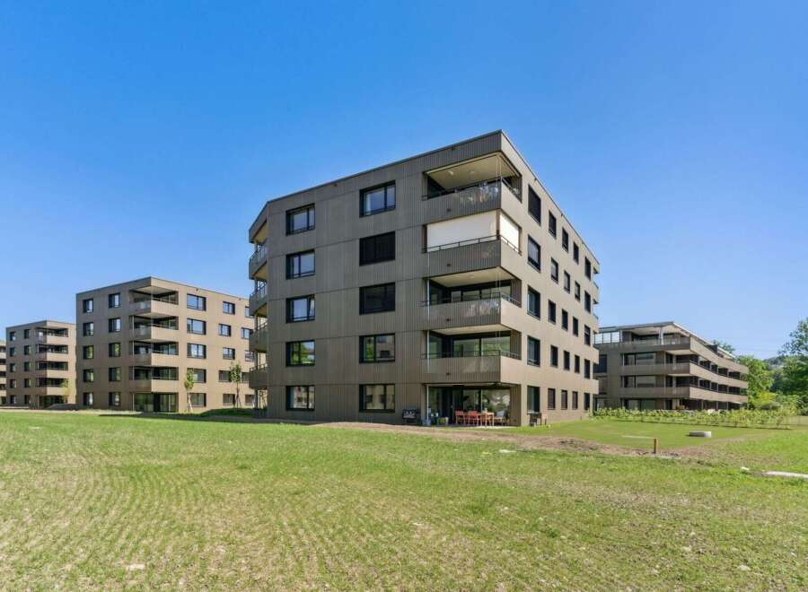 Discover modern living in this contemporary apartment complex, featuring sleek, dark-paneled facades and numerous balconies offering scenic views.
