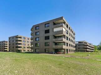 Discover modern living in this contemporary apartment complex, featuring sleek, dark-paneled facades and numerous balconies offering scenic views.