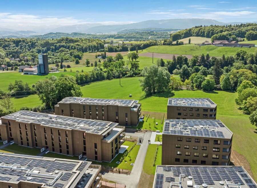 Discover modern living in this expansive residential complex, featuring multiple apartment buildings equipped with state-of-the-art solar panel systems on their rooftops.