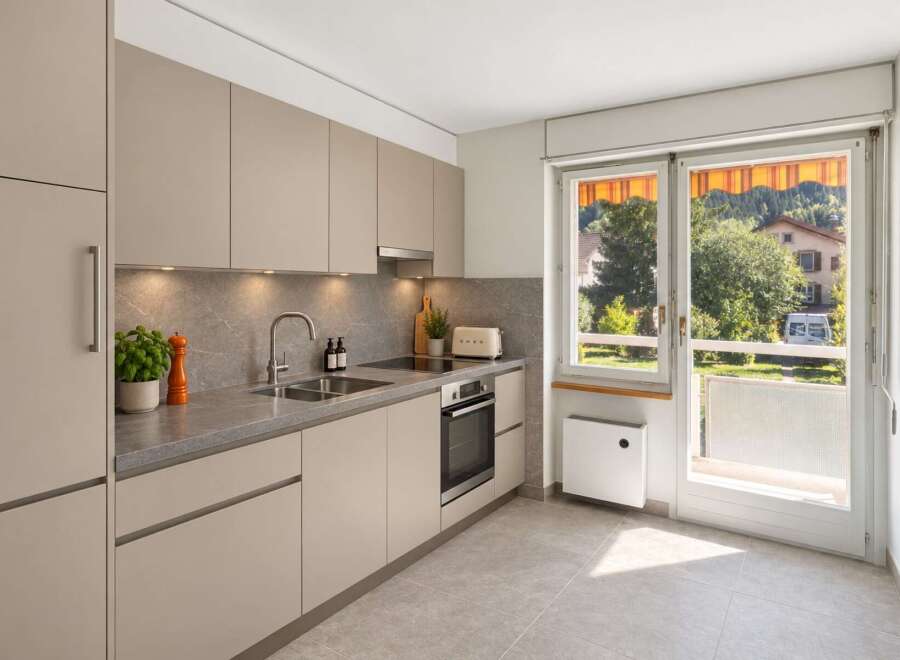 Discover this modern kitchen featuring sleek, taupe cabinetry and a sophisticated stone backsplash.
