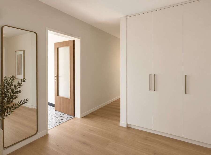Step into a beautifully designed hallway featuring a full-length mirror with a brass frame, reflecting the natural light and adding a touch of elegance.