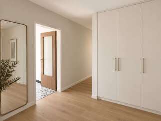 Step into a beautifully designed hallway featuring a full-length mirror with a brass frame, reflecting the natural light and adding a touch of elegance.