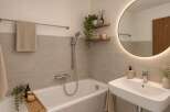 Experience modern comfort in this beautifully appointed bathroom, featuring a sleek bathtub and a stylish vanity with a large, illuminated mirror.