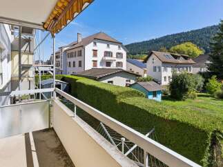 Enjoy the scenic views from this balcony, overlooking a lush green garden and charming residential buildings.