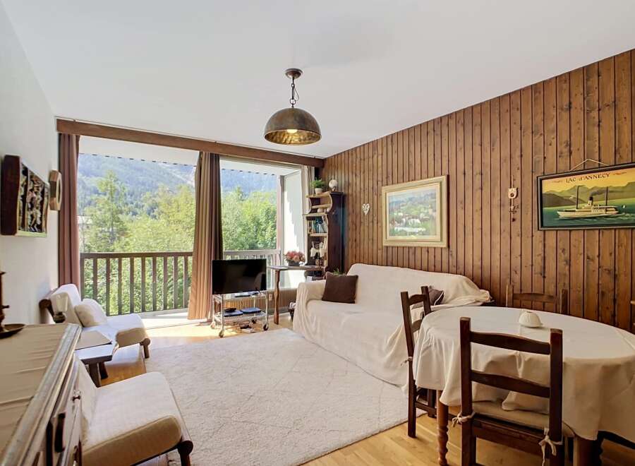 Experience breathtaking mountain views from this charming living room, featuring a cozy seating area and a large window overlooking a lush landscape.