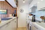 This galley kitchen features a charming wooden accent wall with a framed painting of a boat and a 'CAFFE' sign.