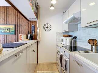 This galley kitchen features a charming wooden accent wall with a framed painting of a boat and a 'CAFFE' sign.