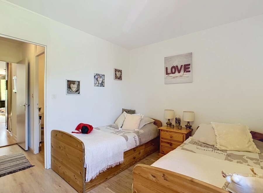 This charming bedroom features two twin beds with wooden frames, perfect for accommodating guests or family.