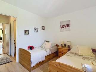 This charming bedroom features two twin beds with wooden frames, perfect for accommodating guests or family.
