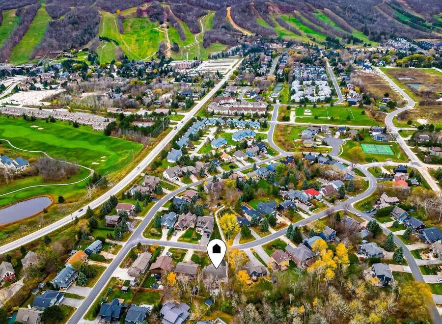 Experience luxury living in this stunning aerial view of a picturesque neighborhood nestled beside a golf course and ski hills.