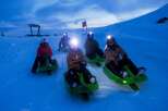 Experience the thrill of night sledding on this picturesque snowy slope.