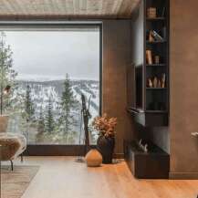 Experience breathtaking mountain views from this luxurious living space, featuring a modern fireplace and a cozy seating area.