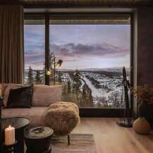 Experience breathtaking mountain views from this luxurious living room, featuring a cozy sectional sofa and a modern fireplace.