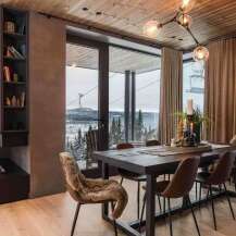 Experience luxurious mountain living in this stunning dining area, featuring a large wooden table perfect for gatherings and plush seating.