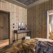 Experience rustic charm in this beautifully appointed bedroom featuring warm, wood-paneled walls and a luxurious fur throw.