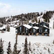 Experience luxury mountain living in this stunning modern chalet, nestled amidst a snowy landscape with breathtaking ski slope views.
