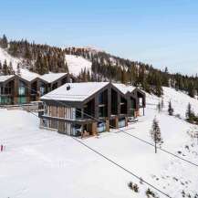 Experience luxury mountain living in these stunning modern chalets, nestled on a snowy slope with breathtaking panoramic views.
