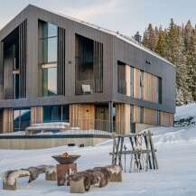 Experience luxury mountain living in this stunning modern chalet, nestled amidst snow-covered pines.