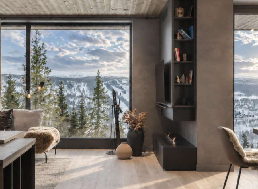 Experience breathtaking mountain views from this modern living space, featuring a cozy seating area with plush cushions and a stylish fireplace.