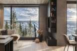 Experience breathtaking mountain views from this modern living space, featuring a cozy seating area with plush cushions and a stylish fireplace.