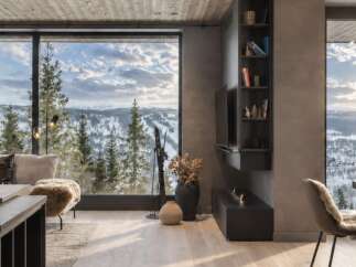 Experience breathtaking mountain views from this modern living space, featuring a cozy seating area with plush cushions and a stylish fireplace.