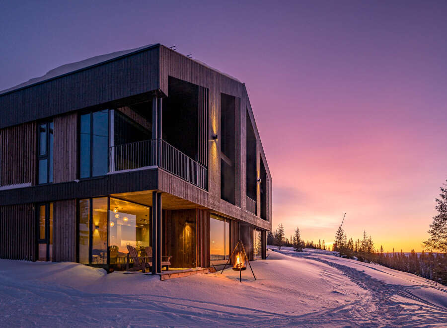 Experience the magic of a winter sunset from this stunning modern home, nestled in a snowy landscape.