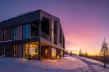 Experience the magic of a winter sunset from this stunning modern home, nestled in a snowy landscape.