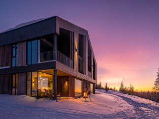 Experience the magic of a winter sunset from this stunning modern home, nestled in a snowy landscape.