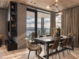 Experience luxury mountain living in this stunning dining area, featuring a sleek dark wood table surrounded by comfortable brown chairs, one adorned with a plush sheepskin throw.