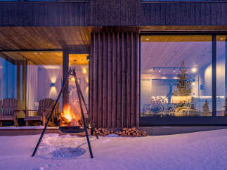 Experience the ultimate cozy retreat in this modern winter cabin, complete with a roaring outdoor fireplace and comfortable Adirondack chairs.