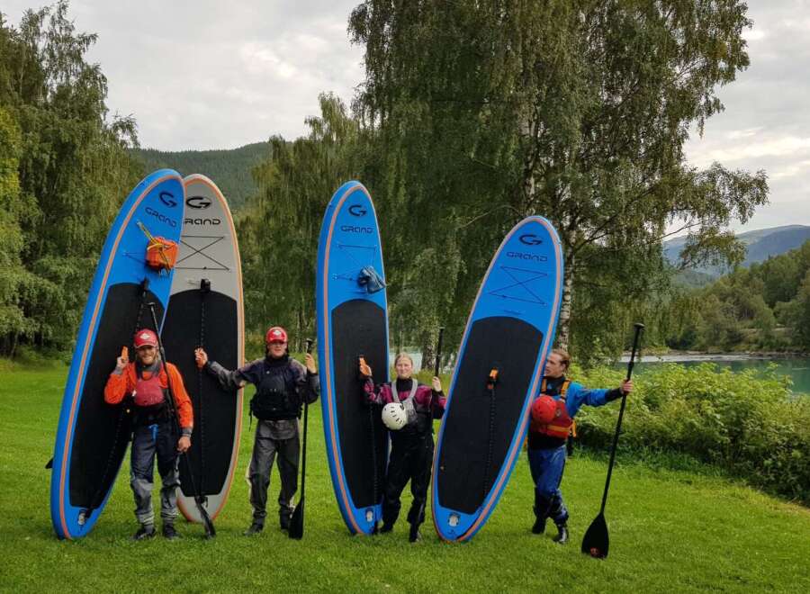 Experience the ultimate outdoor adventure with this group ready for paddleboarding! Surrounded by lush greenery and a serene lake, this scene captures the joy of water sports and exploration.