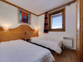 This charming bedroom features two twin beds with plush white comforters, perfect for a cozy mountain retreat.