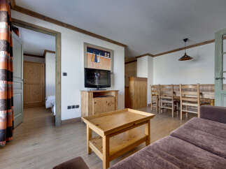 This spacious living area features a cozy seating arrangement with a plush brown sofa and a rustic wooden coffee table.