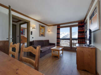 Experience breathtaking mountain views from this charming living area, complete with a comfortable sofa and a rustic wooden coffee table.