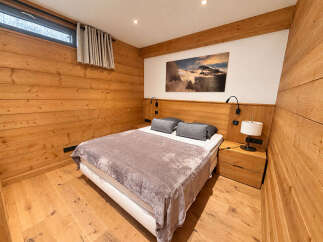 Experience cozy mountain living in this charming bedroom, featuring warm, natural wood paneling throughout and a comfortable queen-sized bed.