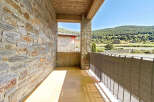Enjoy the serene mountain views from this charming balcony, featuring a rustic stone wall and a tiled floor.