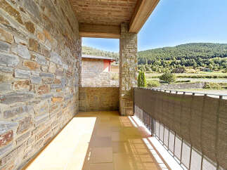 Enjoy the serene mountain views from this charming balcony, featuring a rustic stone wall and a tiled floor.