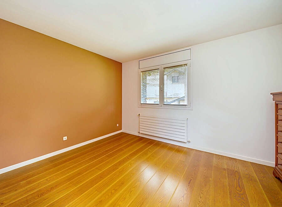 This empty room features a striking accent wall painted in a warm, earthy terracotta hue, contrasting beautifully with the crisp white walls.