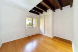 This empty room features a beautiful wooden floor that reflects the natural light streaming in from the large window.