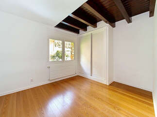 This empty room features a beautiful wooden floor that reflects the natural light streaming in from the large window.