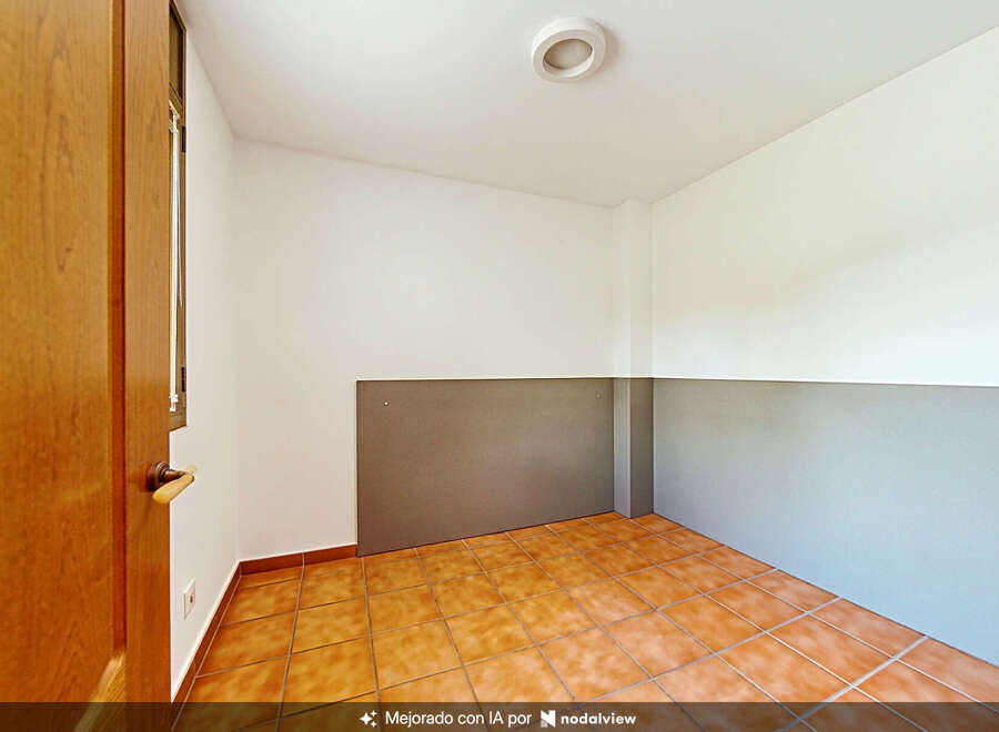 This empty room features warm-toned tiled flooring and neutral-colored walls, offering a blank canvas for customization.