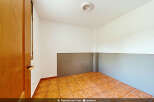 This empty room features warm-toned tiled flooring and neutral-colored walls, offering a blank canvas for customization.