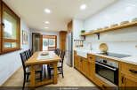 This spacious kitchen and dining area boasts a large wooden dining table with seating for six, perfect for family meals.