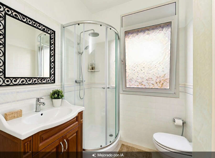 Step into this beautifully appointed bathroom, featuring a sleek corner shower with chrome fixtures and a convenient handheld showerhead.