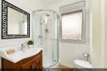 Step into this beautifully appointed bathroom, featuring a sleek corner shower with chrome fixtures and a convenient handheld showerhead.