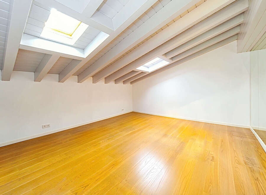 Discover this bright and airy attic space, featuring a stunning vaulted ceiling with exposed white beams and multiple skylights that flood the room with natural light.